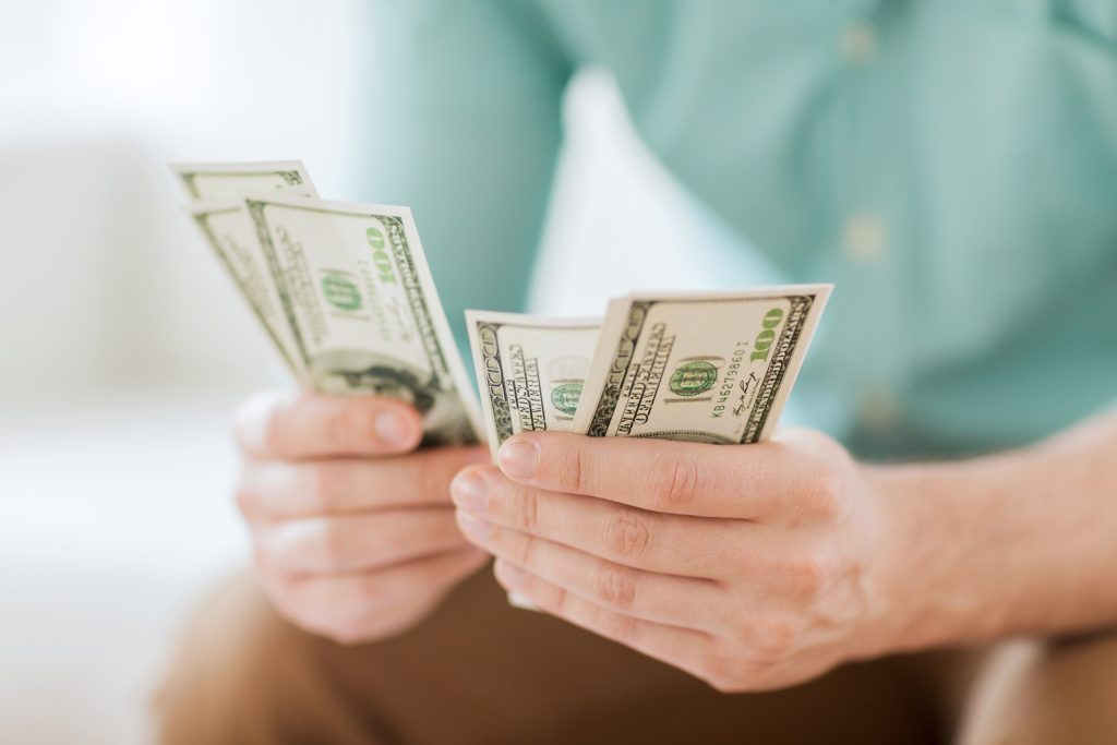 savings, finances, economy and home concept - close up of man counting money at home